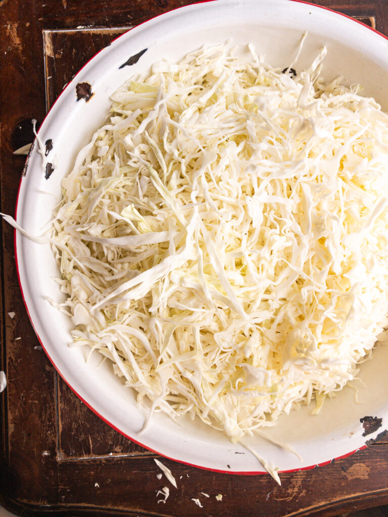 shredded cabbage in white bowl sitting on tabletop