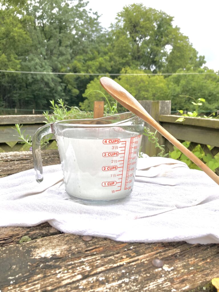 measuring cup filled with hummingbird food with spoon