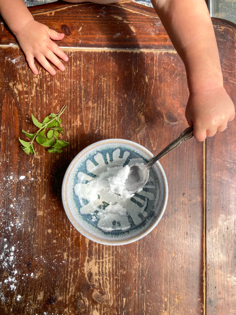 baby scooping homemade toothpaste with a spoon