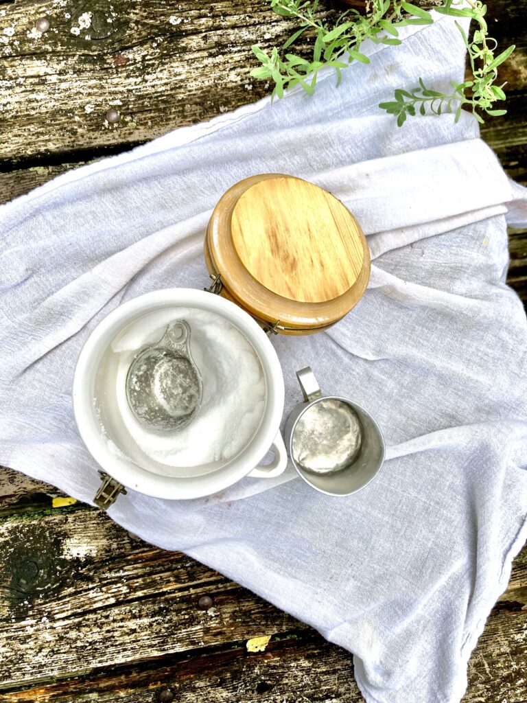 Jar of sugar sitting on a table with a measuring cup